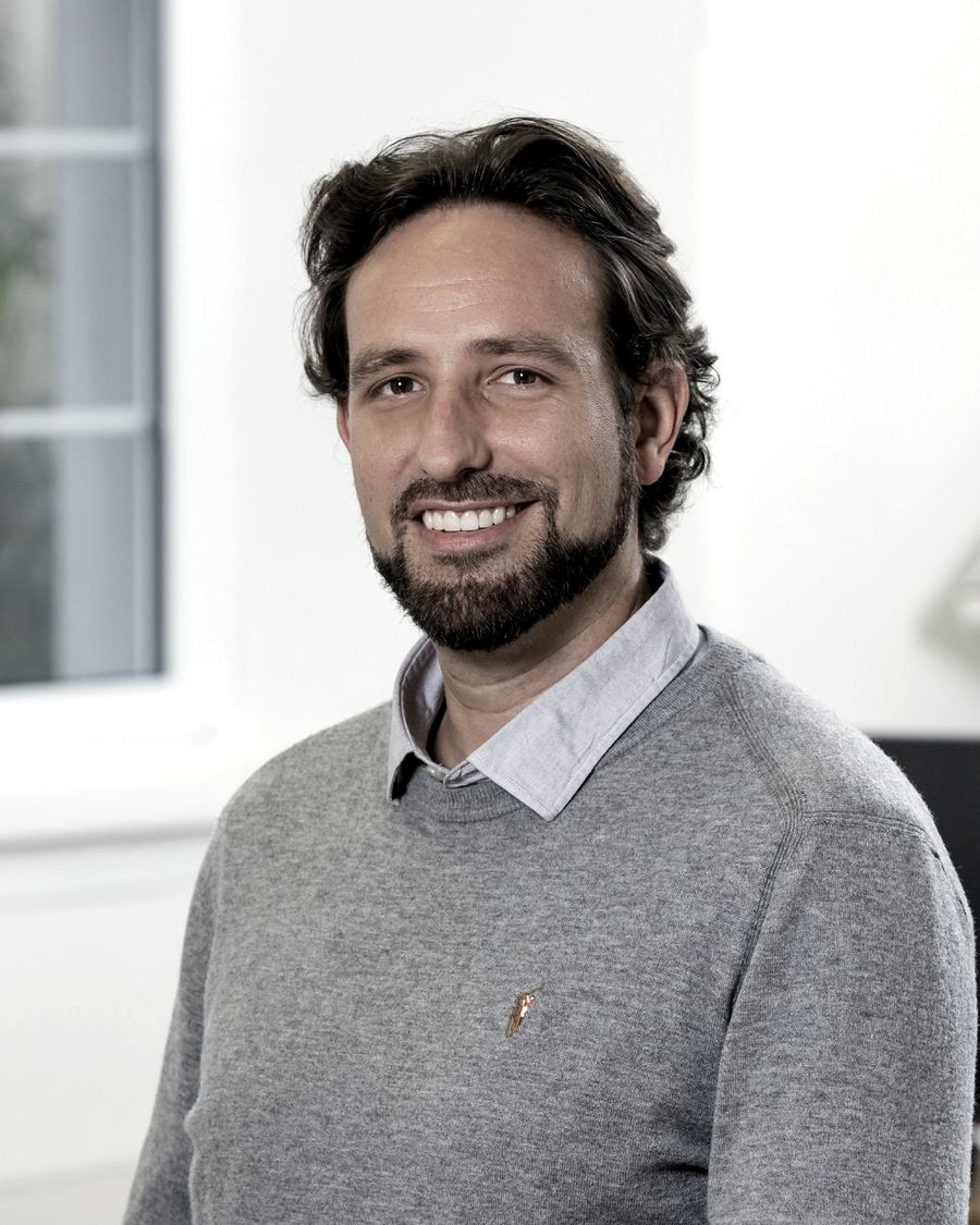 Porträt von Andrea Nicola Weiss, Gründer der fixpunkt gmbh, im grauen Pullover in einem hellen Büro